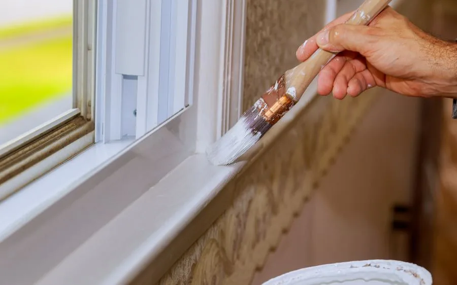 Close-up of a brush laying fresh white paint on a window sill and trim, Boynton Beach, FL