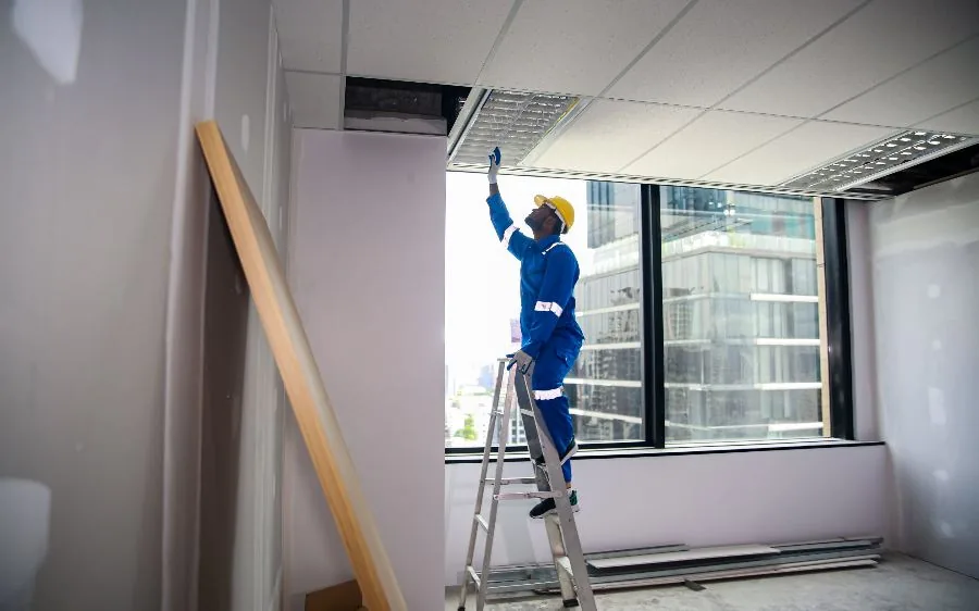 Commercial painter on a ladder prepping an office drop ceiling before repainting, Delray Beach, FL