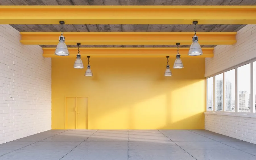 Open commercial space with a freshly painted yellow accent wall and matching painted ceiling beams, Boca Raton, FL