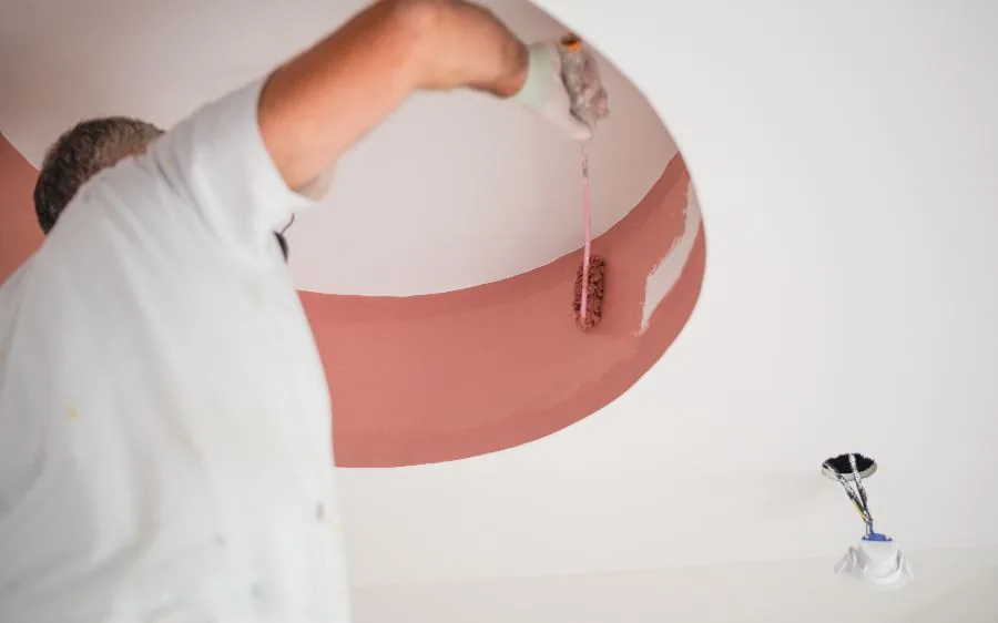 Painter rolling a terracotta accent band onto a curved tray ceiling, Delray Beach, FL